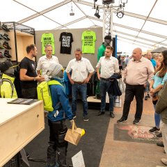 Sabine Breuer (links) und Sascha Groß (2. v.l.) präsentieren Ortsbürgermeister Jochen Becker, dem Beigeordneten Marvin Kraus, Landrat Achim Schwickert und Bürgermeister Andreas Heidrich (von rechts) das Ange-bot von Breuer Workwear + Outdoor.