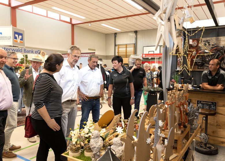 Geschäftsführerin Nicole Sahm (rechts) erläuterte Ortsbürgermeister Jochen Becker (hinten links), Katharina Schlag, Bürgermeister Andreas Heidrich und Landrat Achim Schwickert (vorne von links) das neue Angebot des Holzstudios Sahm, was auch Gesprächsthema von Karsten Lucke, MdEP (hinten 2.v.l.) und Ulrich Theis (hinten rechts) war.