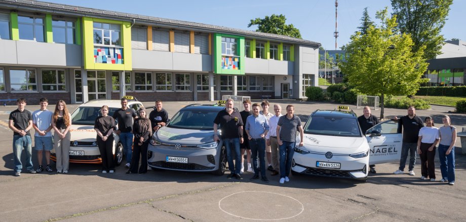 eine Gruppe Menschen mit Taxis auf dem Schulhof