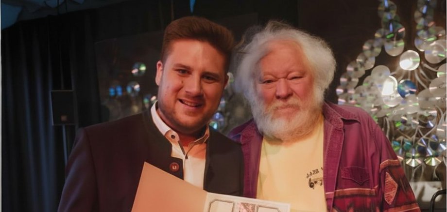 Im Rahmen des Konzerts von Matthias „Biber“ Herrmann als Teil der Reihe „Jazz we can“ in der Praxis für Ergotherapie in Bad Marienberg überreichte Bürgermeister Mar-vin Kraus (links) unter großem Applaus des Publikums den Kulturpreis der Verbands-gemeinde Bad Marienberg an Hans Ruppert.