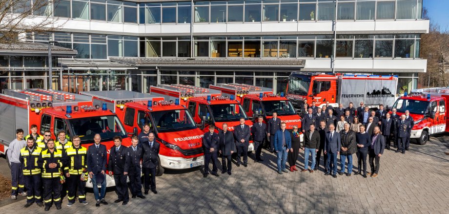 Feuerwehrleute und Teilnehmer der Veranstaltung stehen vor den neuen Fahrzeugen