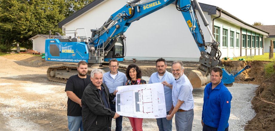 Vertreter von Verwaltung, Schule und Bauunternehmen auf der Baustelle.