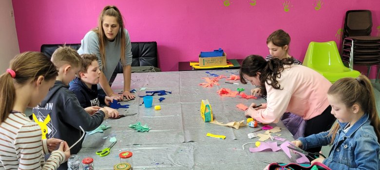 Kinder sitzen an einem Tisch und basteln.