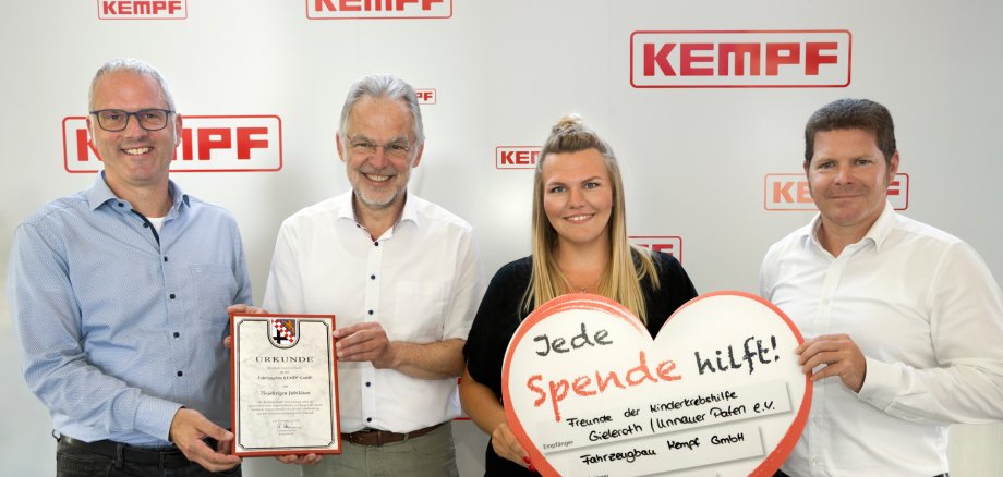 Für die beispielhafte Entwicklung sowie die außerordentlichen wirtschaftlichen Leistungen für die heimische Region sprach Bürgermeister Andreas Heidrich (2. V. l.) der Firma Fahrzeugbau Kempf GmbH Lob und Anerkennung aus und überreichte eine entsprechende Urkunde der Verbandsgemeinde Bad Marienberg an die Geschäftsführer Daniel Dreßler (rechts) und Manuel Kempf (links). 
Ein weiterer freudiger Anlass war die Spendenübergabe der Fa. Fahrzeugbau Kempf GmbH an die Freunde der Kinderkrebshilfe Gieleroth / Unnauer Paten e.V.
Anlässlich des Jubiläums hatte das Unternehmen bei den Feierlichkeiten um Spenden gebeten. Die stolze Summe von 15.000 Euro nahm die Vorsitzende der Kinderkrebshilfe, Ramona Fischer, sichtlich erfreut und sehr dankbar entgegen.
