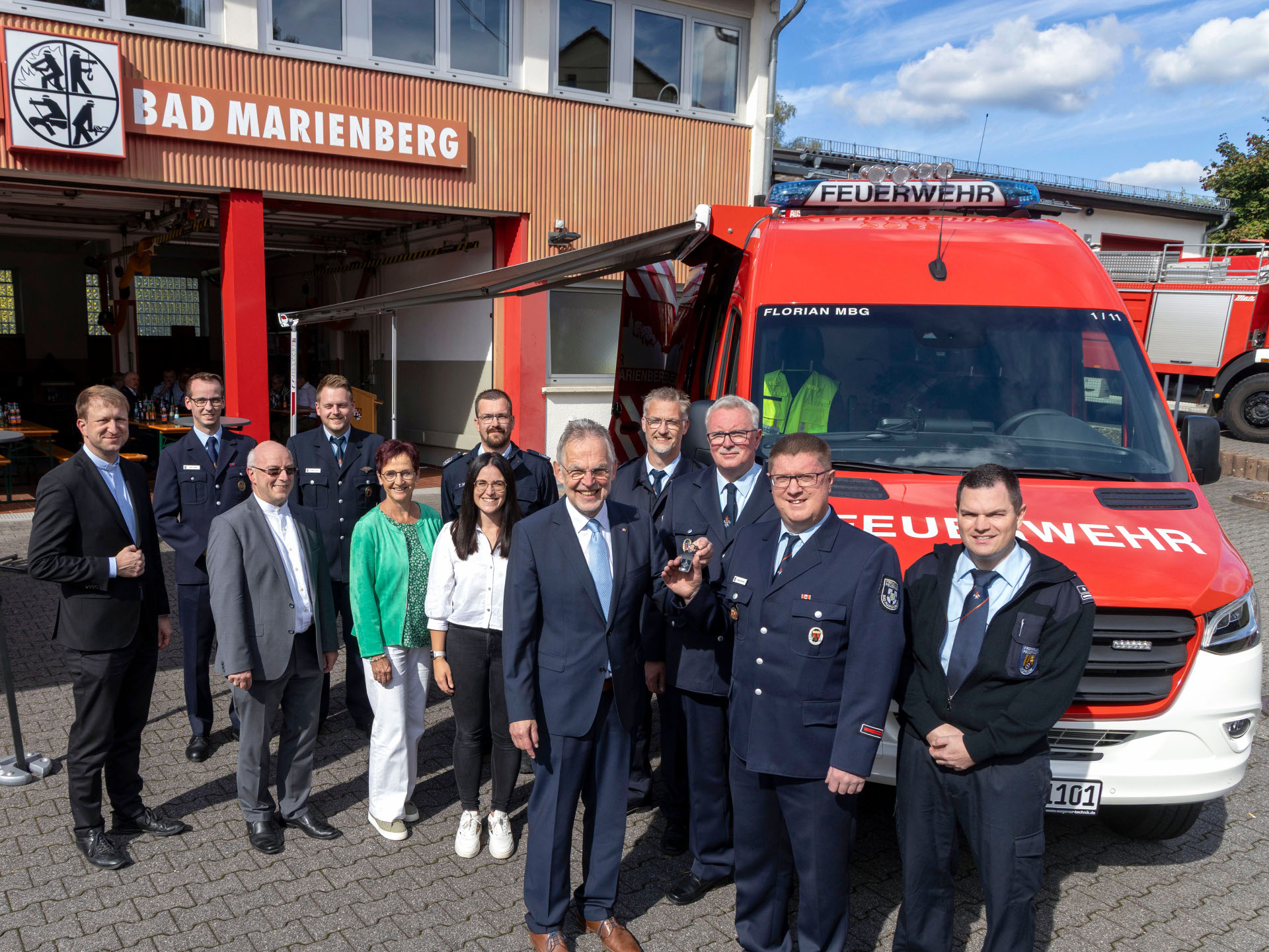 Schlüsselübergabe für den modernen Einsatzleitwagen (ELW) durch den Dienstherrn der Feuerwehren in der Verbandsgemeinde Bad Marienberg, Bürgermeister Andreas Heidrich (5.v.r.) an Wehrführer Sascha Stimper (2.v.r.). Der Stellvertretende Brand- und Katastrophenschutzinspekteur Markus Brenner (4.v.r.) sowie die Wehrleitung der Verbandsgemeinde Bad Marienberg, Frank Schiffmann (3.v.r.) und Tobias Schüler (rechts) freuten sich ebenso über das neue Fahrzeug wie die stellvertretenden Wehrführer Kevin Unger (2.v.l.) und Veikko Grönert (4.v.l.). Zu den Gratulanten zählten ebenfalls Thomas Mönnich für den Kreisfeuerwehrverband (hinten Mitte), für die Kirchengemeinden Pfarrer Peter Wagner (3.v.l.) und Pfarrer Benedikt Wach (links). Für die Verbandsgemeindeverwaltung waren Fachbereichsleiterin Doris Wengenroth und Sachbearbeiterin Lara Held dabei.