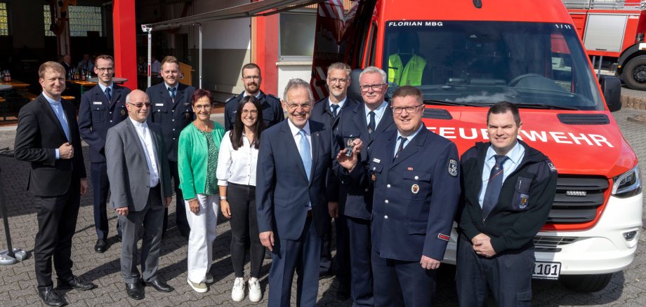 Schlüsselübergabe für den modernen Einsatzleitwagen (ELW) durch den Dienstherrn der Feuerwehren in der Verbandsgemeinde Bad Marienberg, Bürgermeister Andreas Heidrich (5.v.r.) an Wehrführer Sascha Stimper (2.v.r.). Der Stellvertretende Brand- und Katastrophenschutzinspekteur Markus Brenner (4.v.r.) sowie die Wehrleitung der Verbandsgemeinde Bad Marienberg, Frank Schiffmann (3.v.r.) und Tobias Schüler (rechts) freuten sich ebenso über das neue Fahrzeug wie die stellvertretenden Wehrführer Kevin Unger (2.v.l.) und Veikko Grönert (4.v.l.). Zu den Gratulanten zählten ebenfalls Thomas Mönnich für den Kreisfeuerwehrverband (hinten Mitte), für die Kirchengemeinden Pfarrer Peter Wagner (3.v.l.) und Pfarrer Benedikt Wach (links). Für die Verbandsgemeindeverwaltung waren Fachbereichsleiterin Doris Wengenroth und Sachbearbeiterin Lara Held dabei.